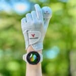 Voice Caddie A2 Golf GPS Watch as on a wrist with a golf glove on and holding a golf ball.