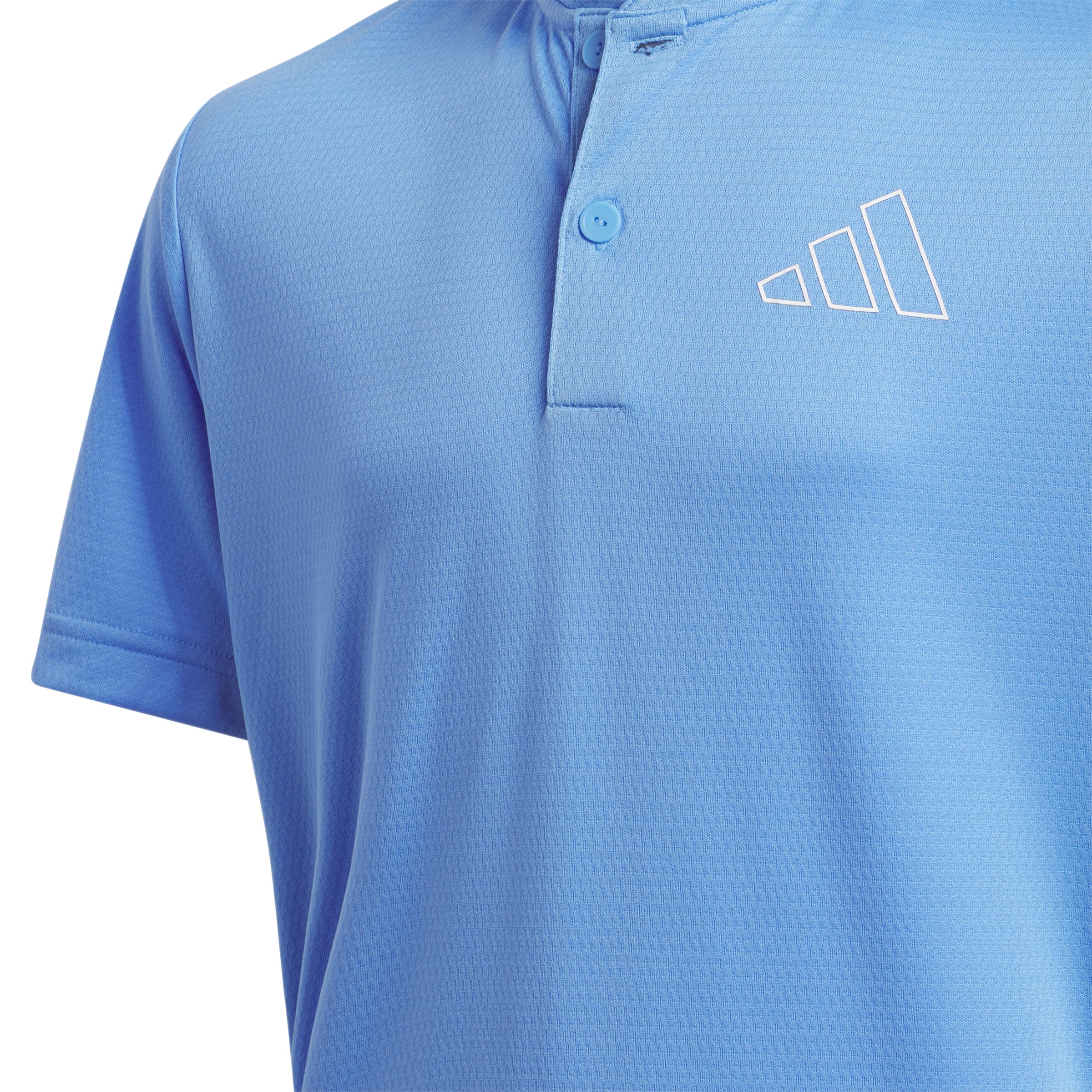 Close up of this adidas boys golf shirt, showing the contrast logo in yellow against the blue shirt.