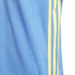 Showing the close up details of the adidas boys polo shirt with the yellow 3 stripe contrast details on the polo against the bright blue shirt.